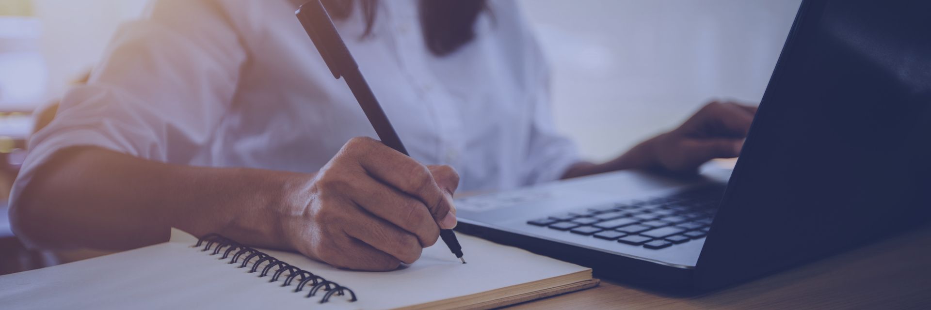 Person writing sth on paper and the other hand is touching a touchpad